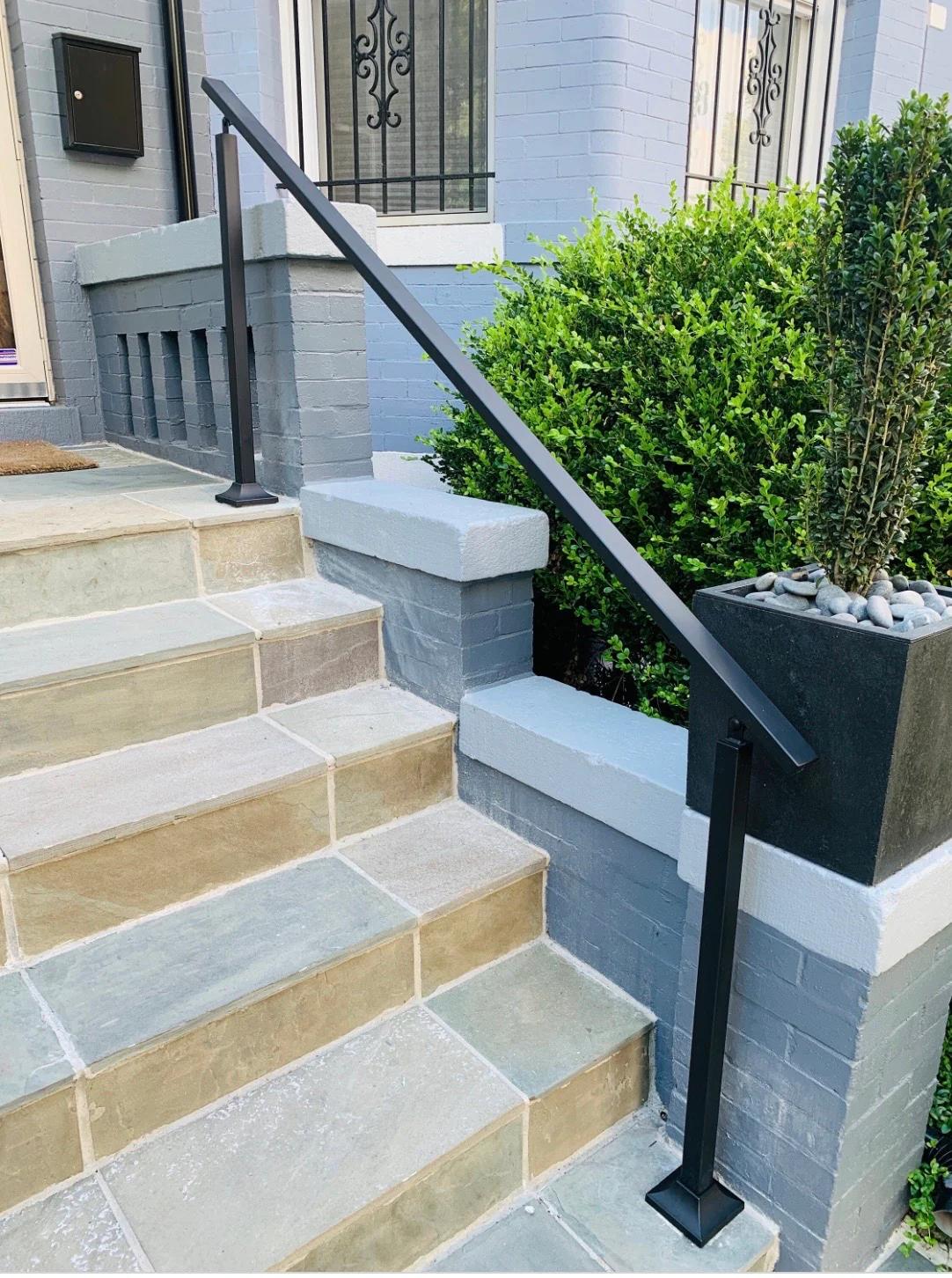 Black metal handrail installed on stone front steps