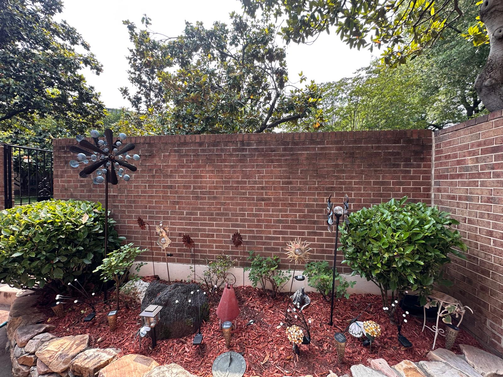 Decorative garden bed with shaped shrubs, red mulch and ornaments