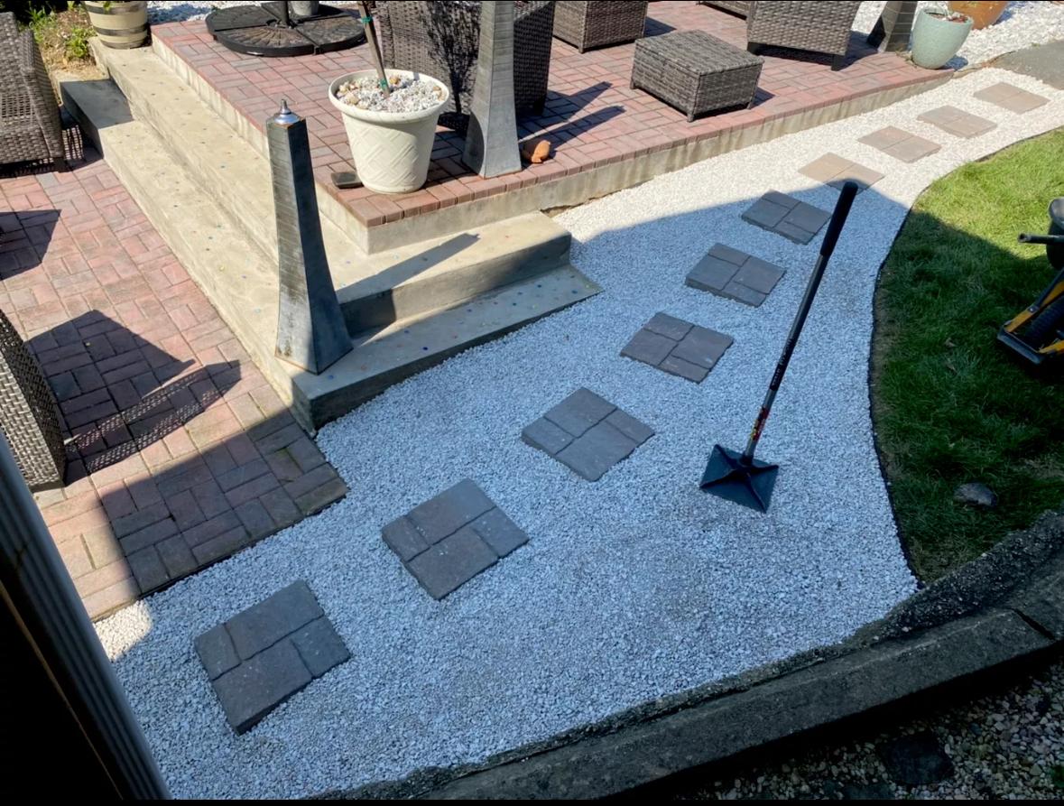 White gravel walkway with square stepping stones beside a patio